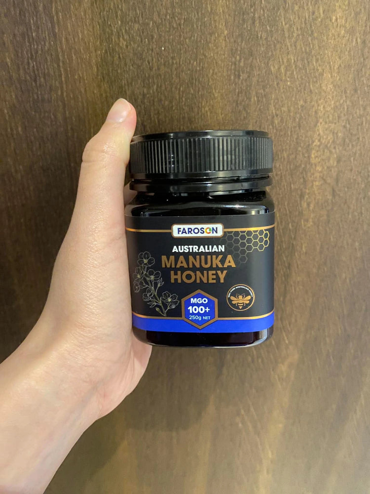 Hand holding a jar of Farson Australian Manuka Honey against a wooden background